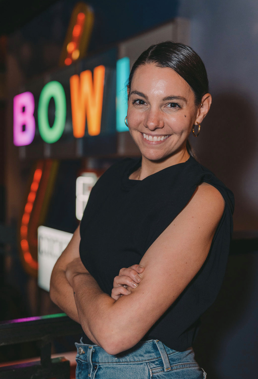 Image of alumna Carissa Del Bene in front of sign for Bowlero Corp.