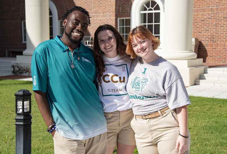 Three students smile and face the camera while standing in the Edwards Courtyard