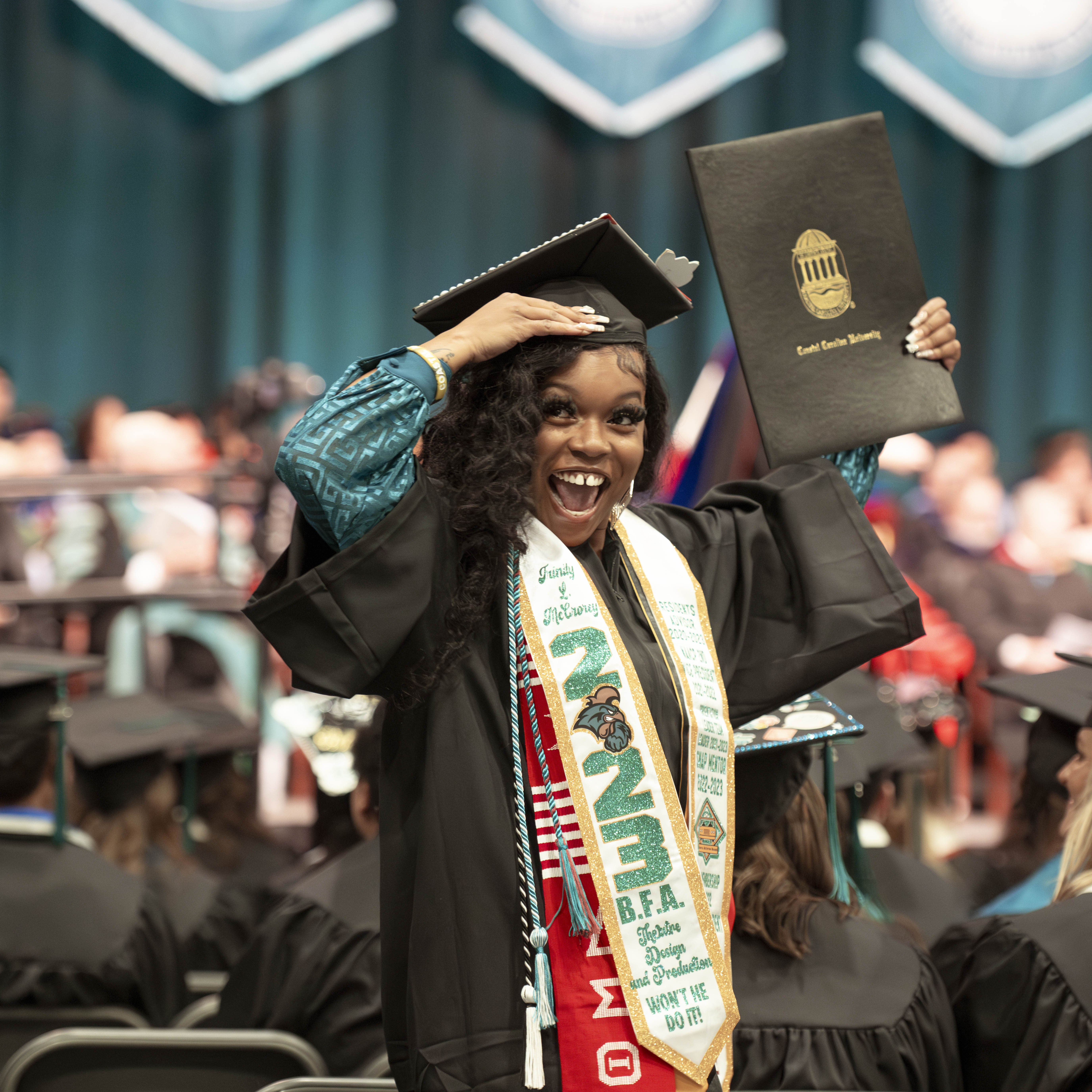 Student in regalia holding up diploma at fall commencement